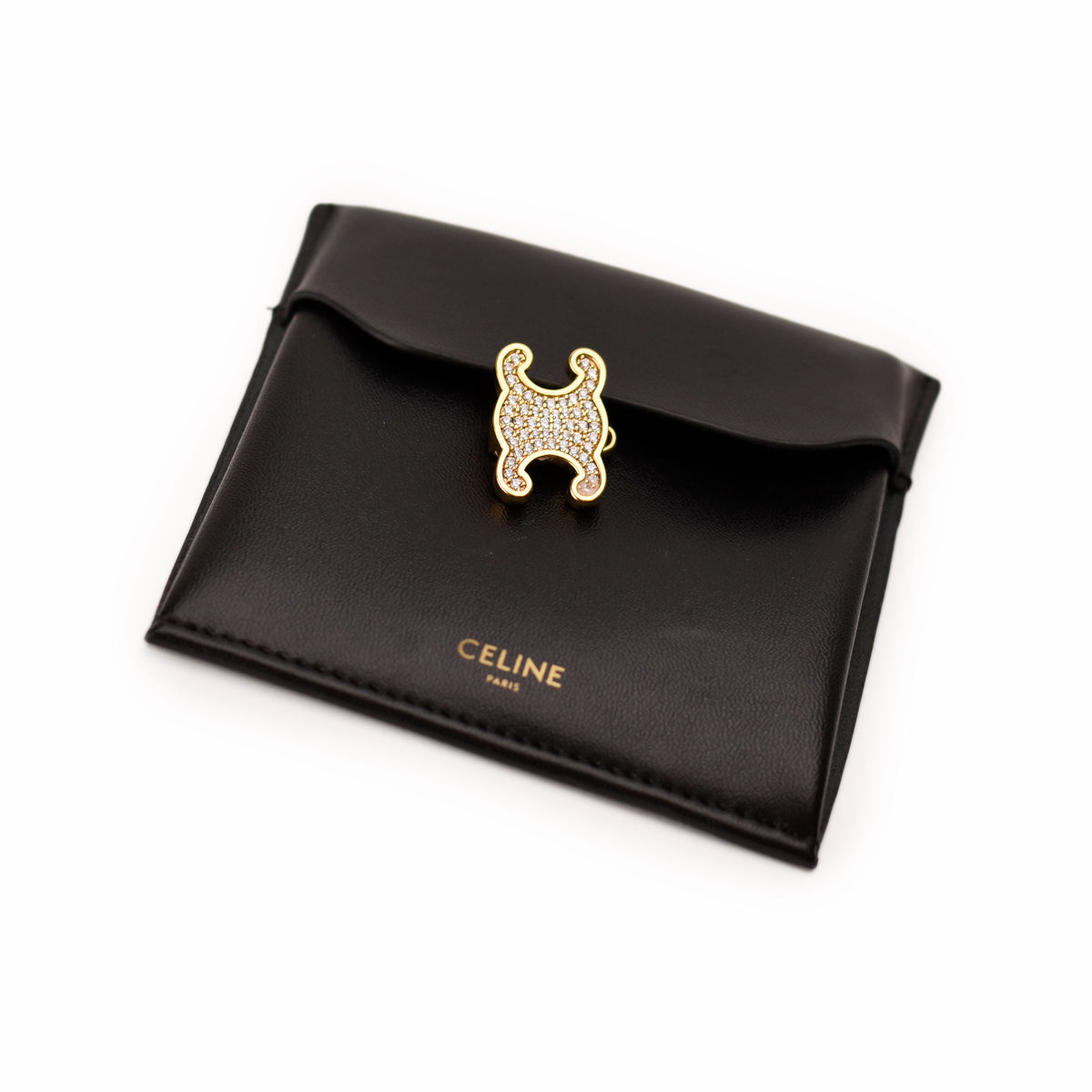 A black leather Celine card holder featuring the signature Celine horse logo charm embellished with pavé crystals in gold-tone metal, with the gold CELINE PARIS logo printed below.