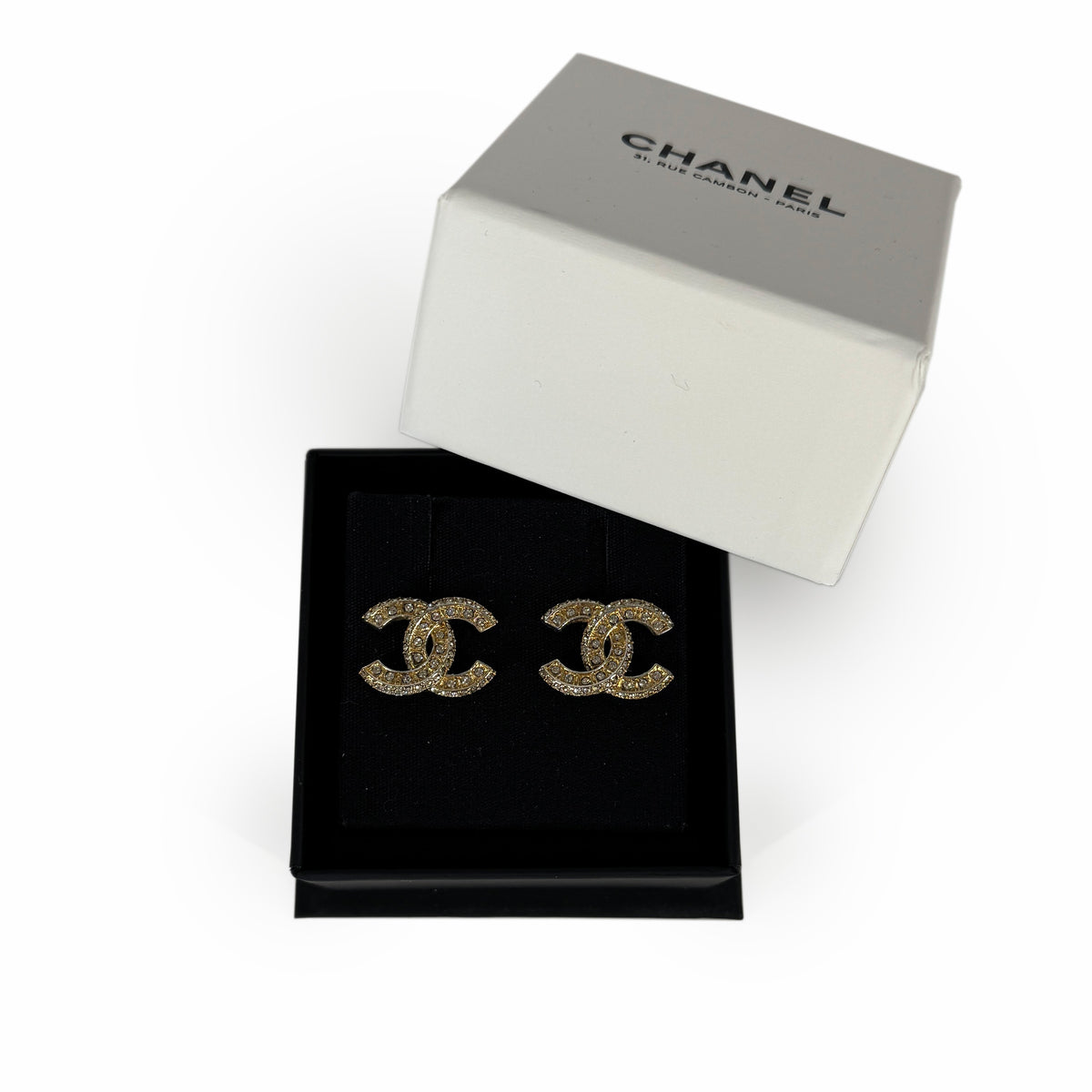 Gold-tone Chanel interlocking CC logo stud earrings in a black jewelry box, curated Pre-loved Luxury by Myluxe in Helsinki.