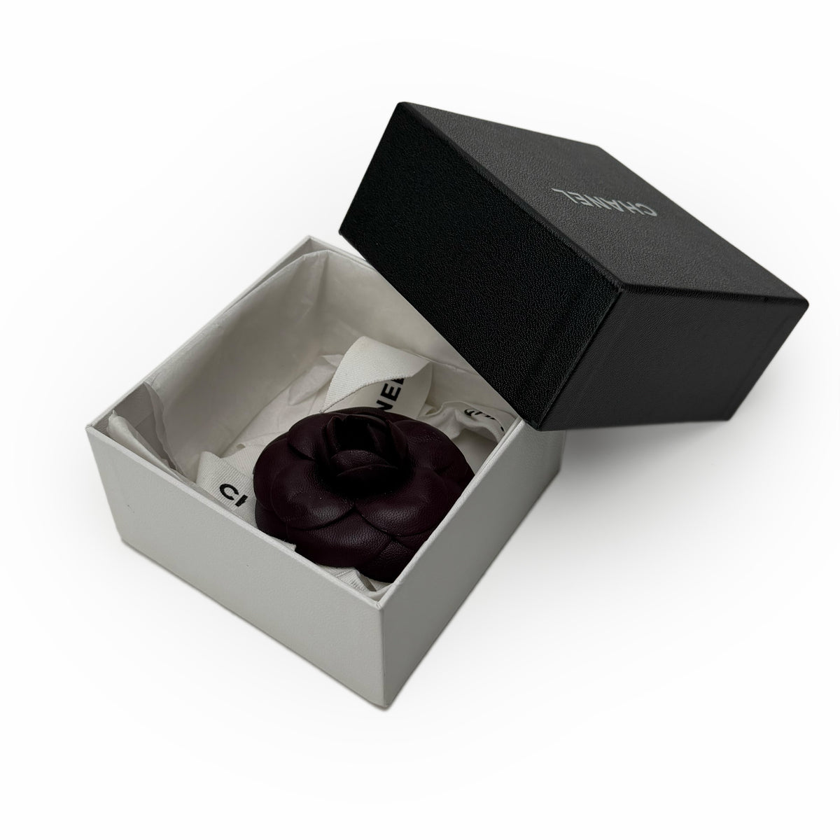Black leather Chanel rose brooch in a designer gift box, curated Pre-loved Luxury by Myluxe in Helsinki.