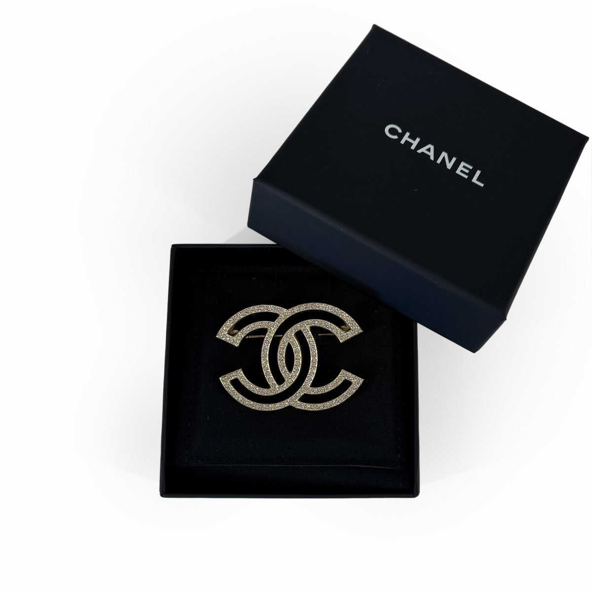 Chanel gold-tone interlocking CC crystal brooch in a black gift box, curated Pre-loved Luxury by Myluxe in Helsinki.