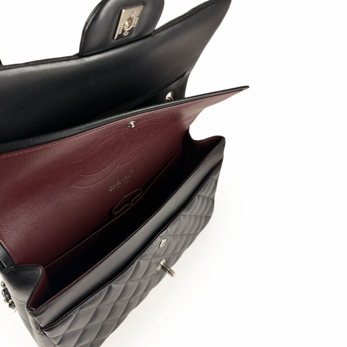 Open black quilted leather Chanel flap bag with burgundy interior, curated Pre-loved Luxury by Myluxe in Helsinki.