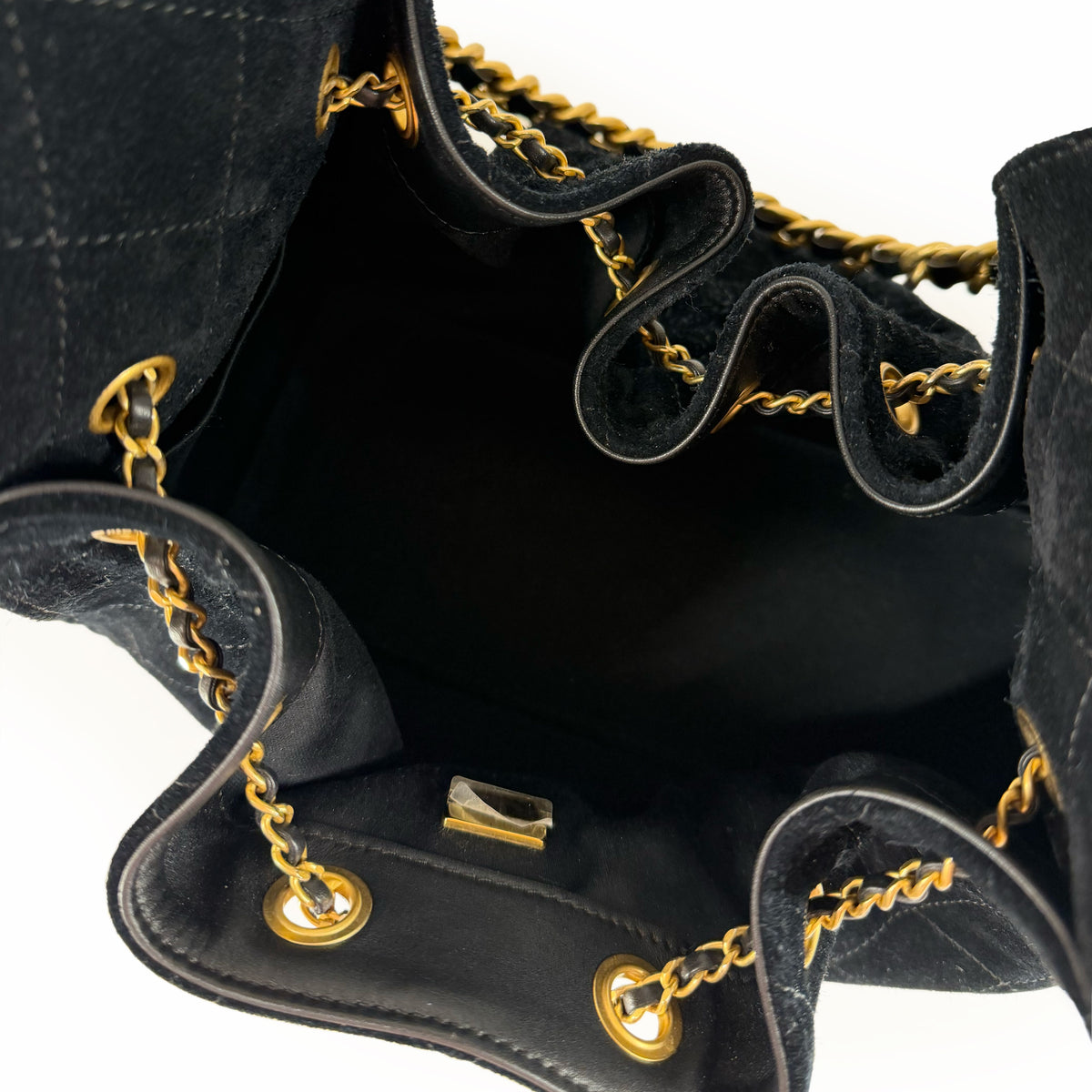 Interior view of a black quilted suede luxury handbag with gold-tone chain detail, curated Pre-loved Luxury by Myluxe in Helsinki.