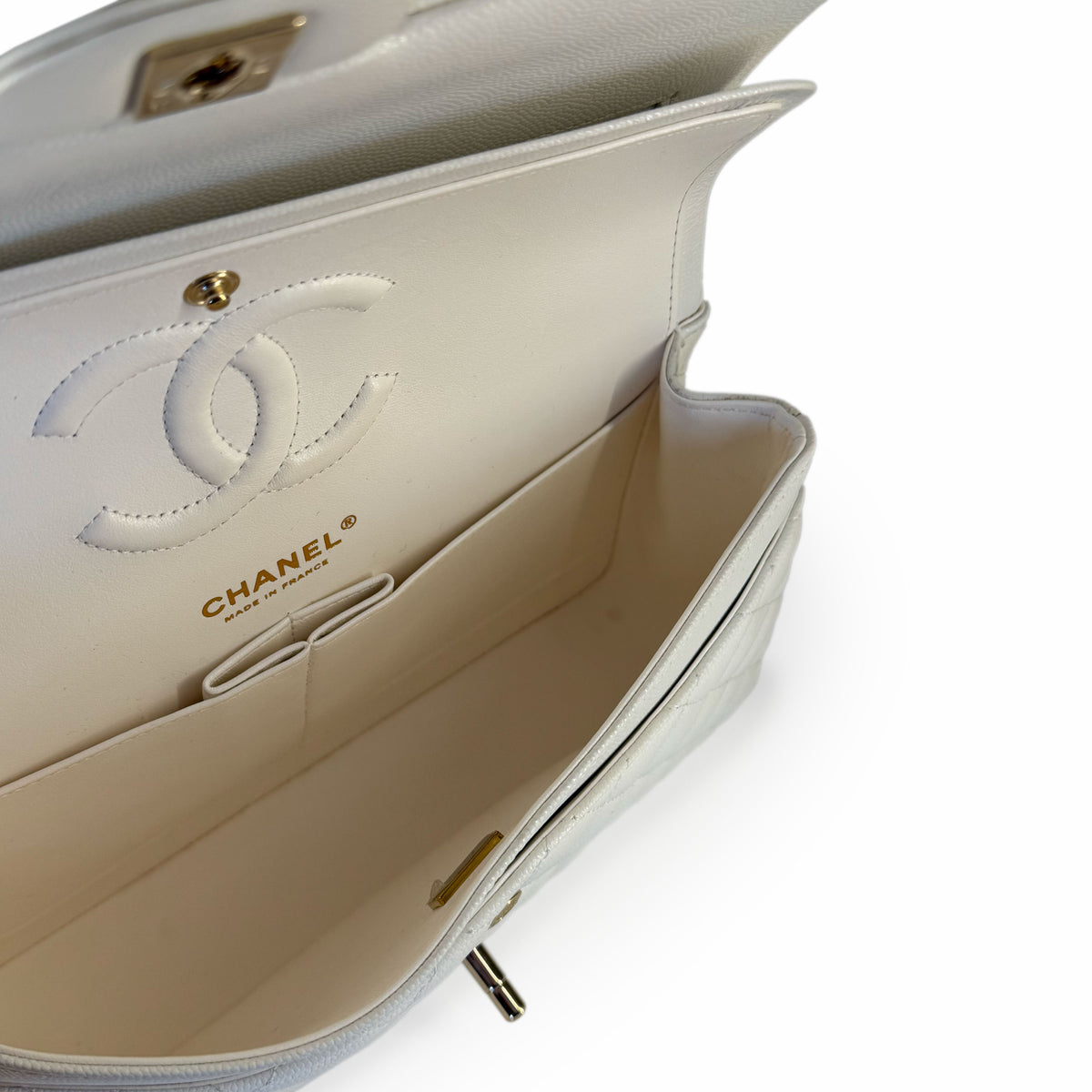 Interior of a white Chanel quilted leather handbag with gold hardware, curated Pre-loved Luxury by Myluxe in Helsinki.