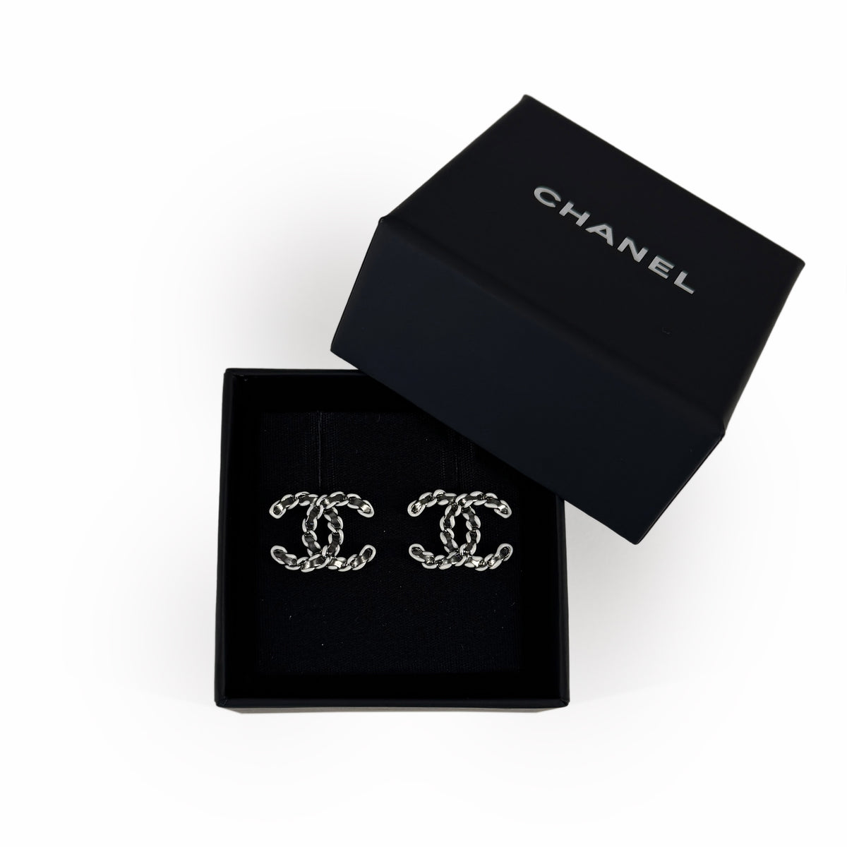 Silver-tone Chanel interlocking CC logo stud earrings in a black box, curated Pre-loved Luxury by Myluxe in Helsinki.