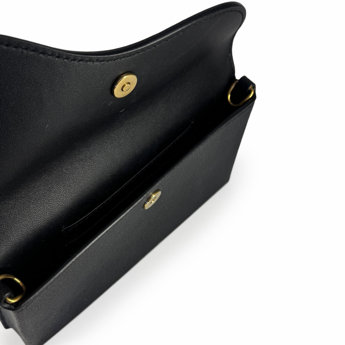 Interior view of a black leather handbag with gold-tone magnetic snap closure, curated Pre-loved Luxury by Myluxe in Helsinki.