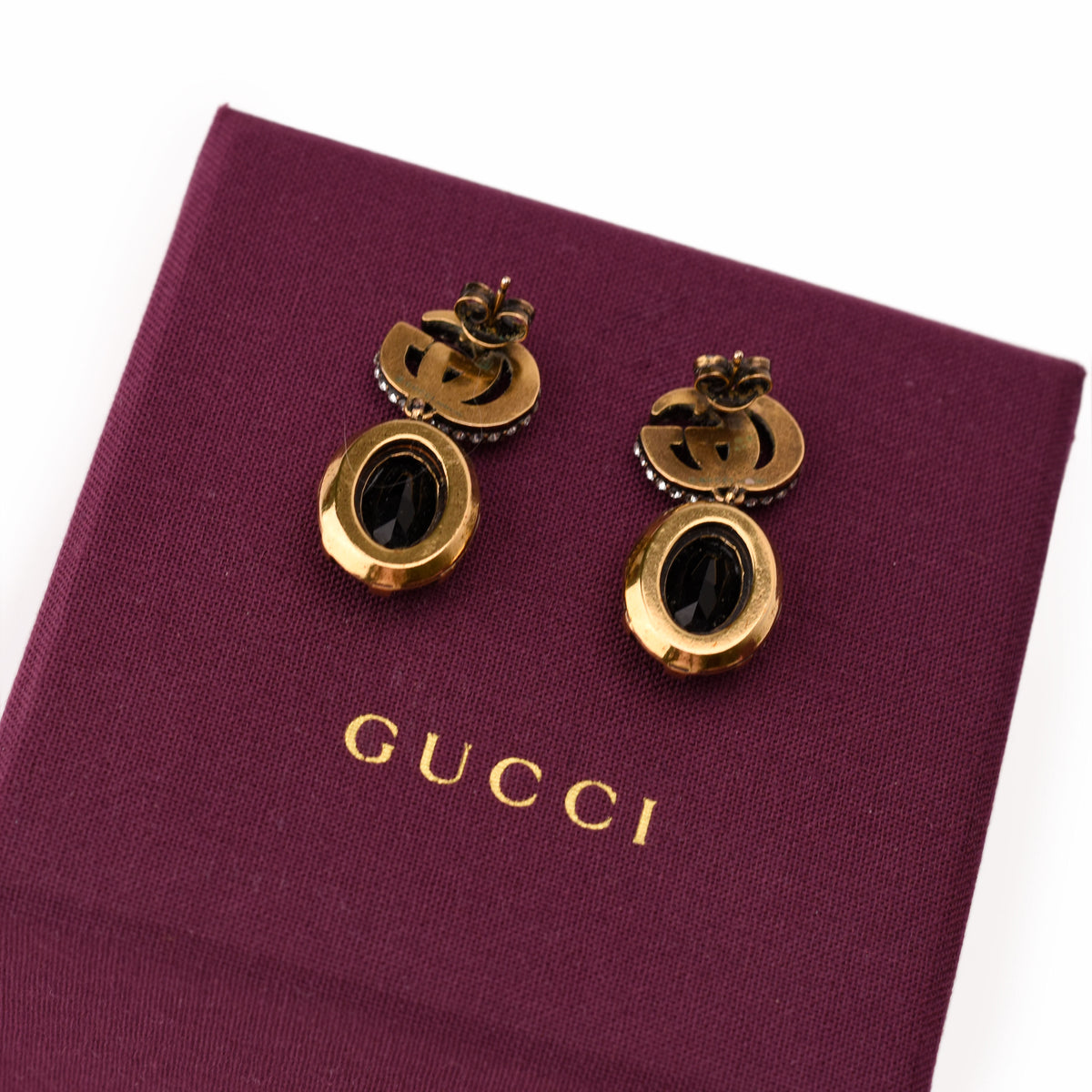 Gold-tone Gucci earrings with black crystals on a burgundy box, curated Pre-loved Luxury by Myluxe in Helsinki.