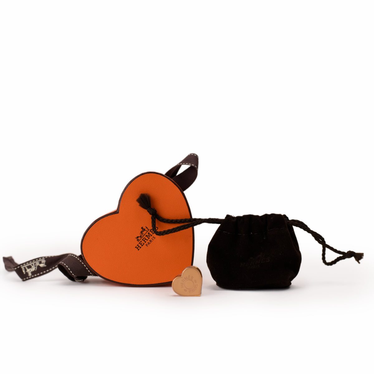 Hermès orange leather heart-shaped accessory with dark brown strap. curated Pre-loved Luxury by Myluxe in Helsinki.