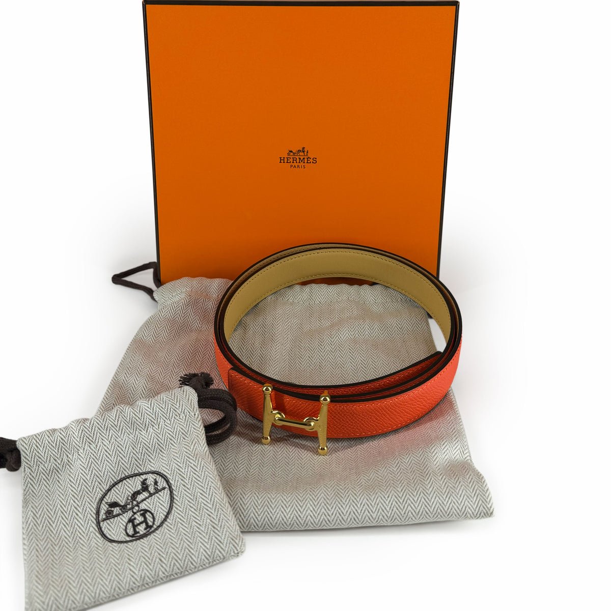Hermès orange leather belt with gold H buckle and dust bags, curated Pre-loved Luxury by Myluxe in Helsinki.