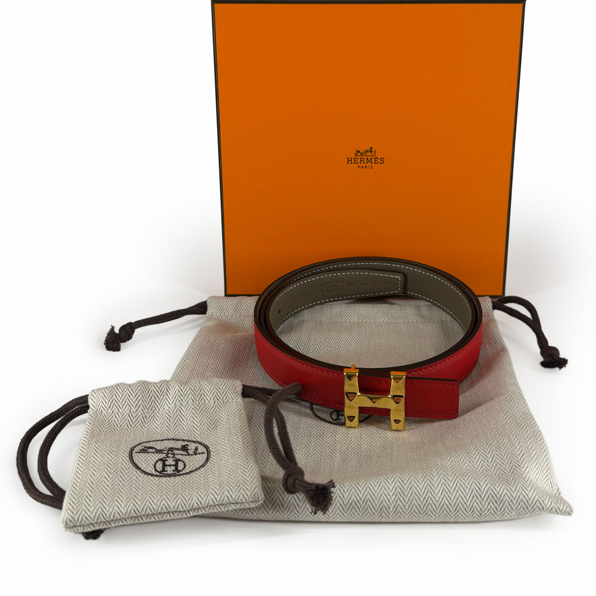 Red leather Hermès belt with gold-tone H buckle and dust bags, curated Pre-loved Luxury by Myluxe in Helsinki.