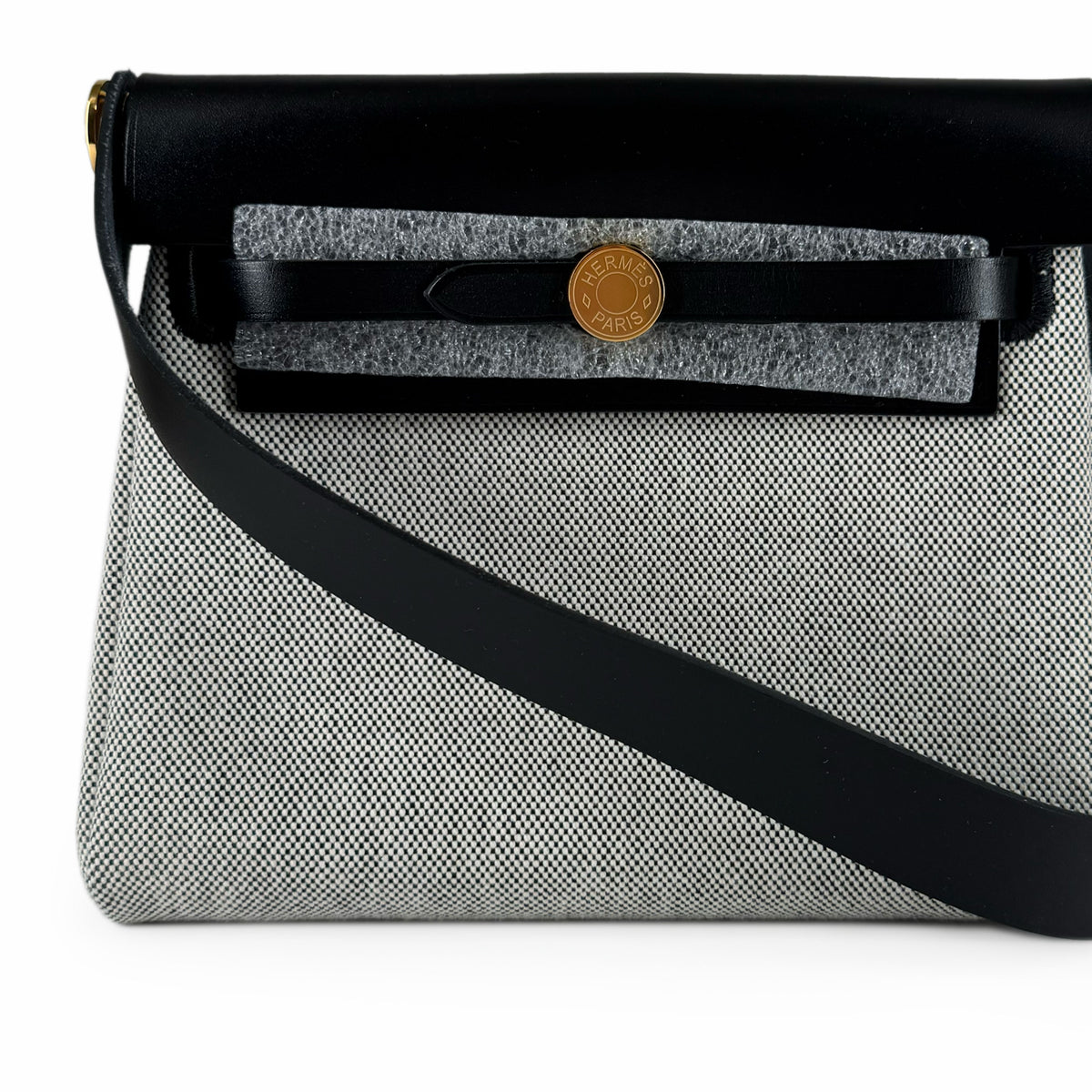 Hermès grey canvas and black leather crossbody bag with gold hardware, curated Pre-loved Luxury by Myluxe in Helsinki.
