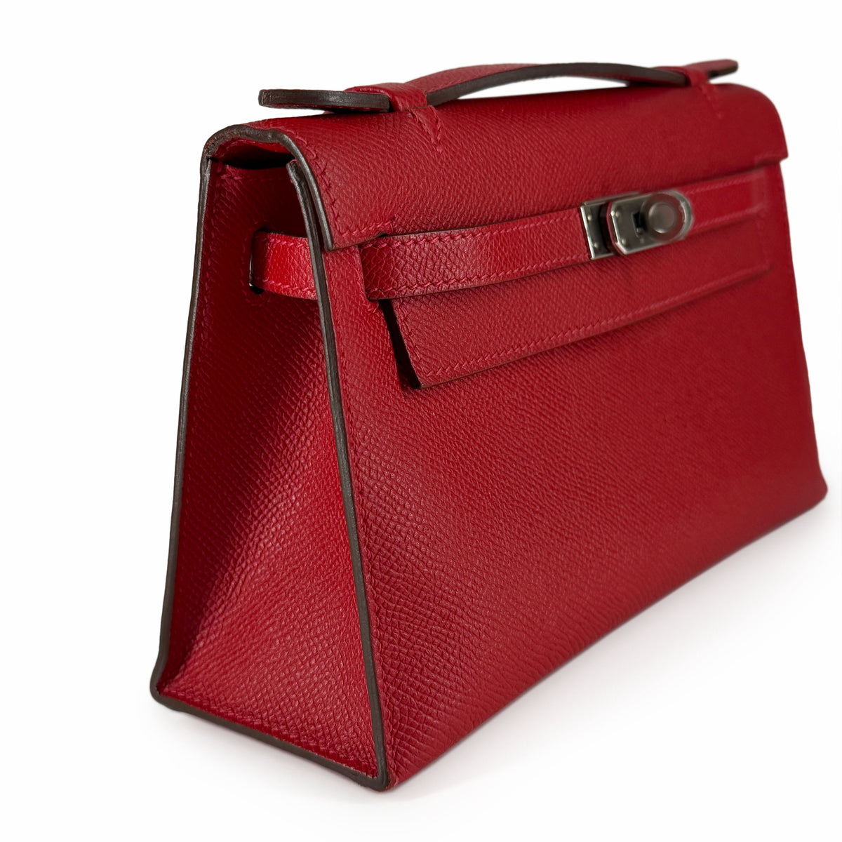Red textured leather trapezoid handbag with top handle and turn-lock closure, curated Pre-loved Luxury by Myluxe in Helsinki.