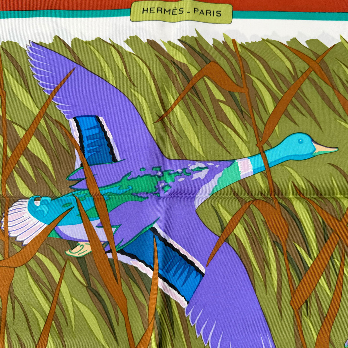 Hermès purple and blue silk scarf featuring a stylized duck in grass, curated Pre-loved Luxury by Myluxe in Helsinki.