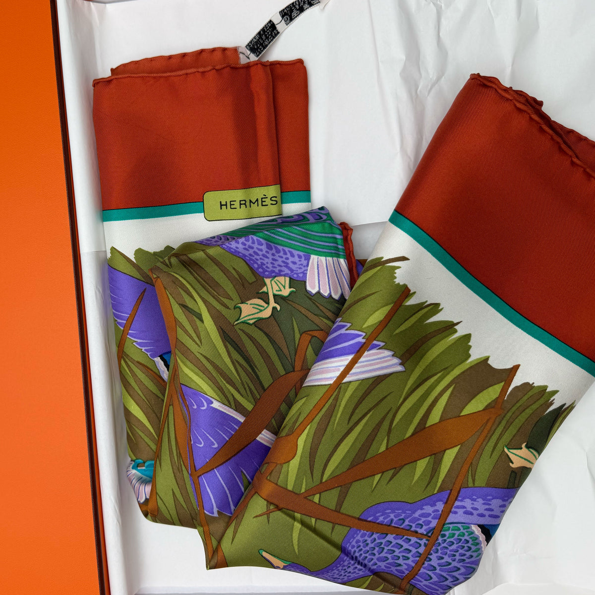 Rust orange Hermès silk scarf with colorful bird and nature print, curated Pre-loved Luxury by Myluxe in Helsinki.