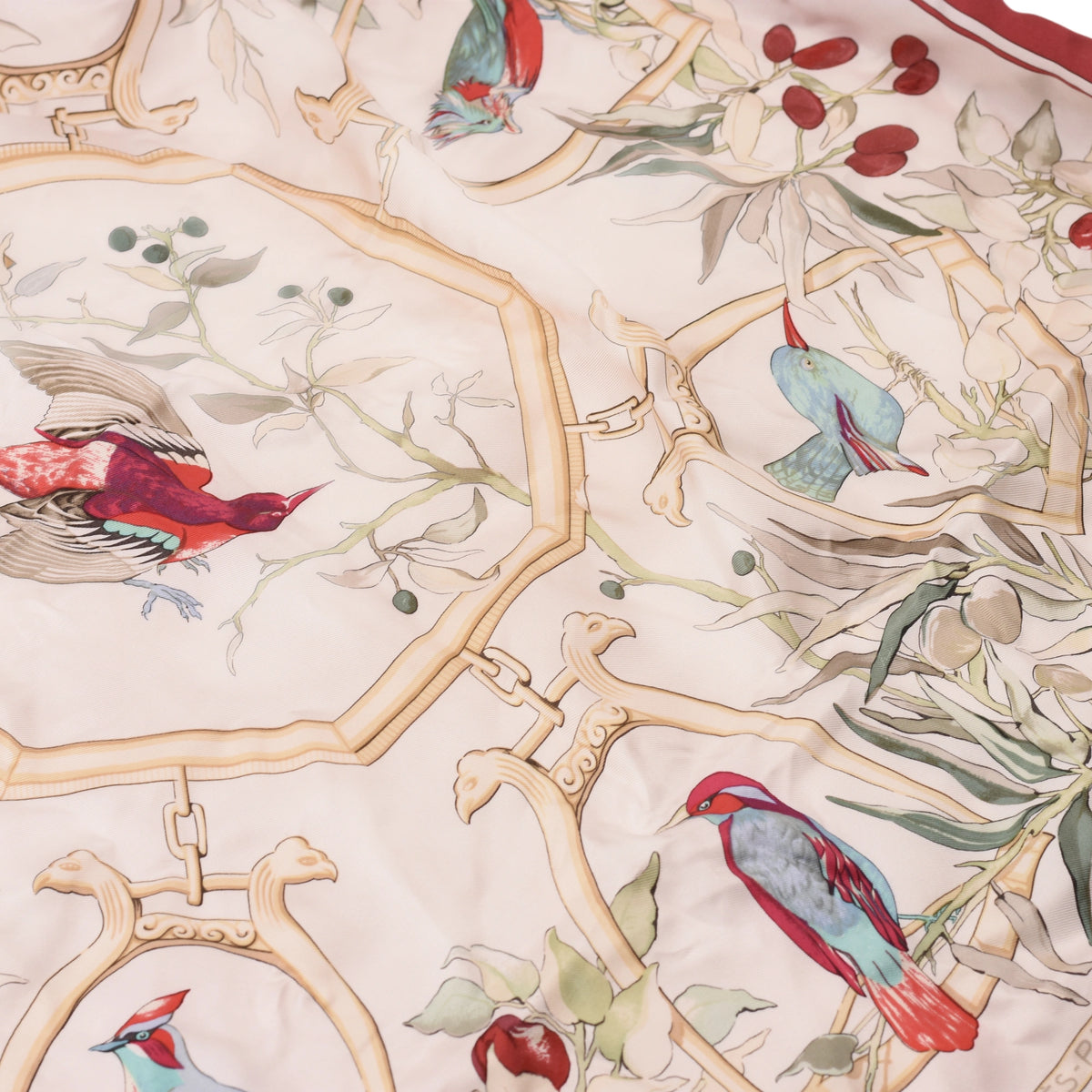 Detailed view of beige Hermès silk scarf featuring colorful bird and botanical motifs. curated Pre-loved Luxury by Myluxe in Helsinki.