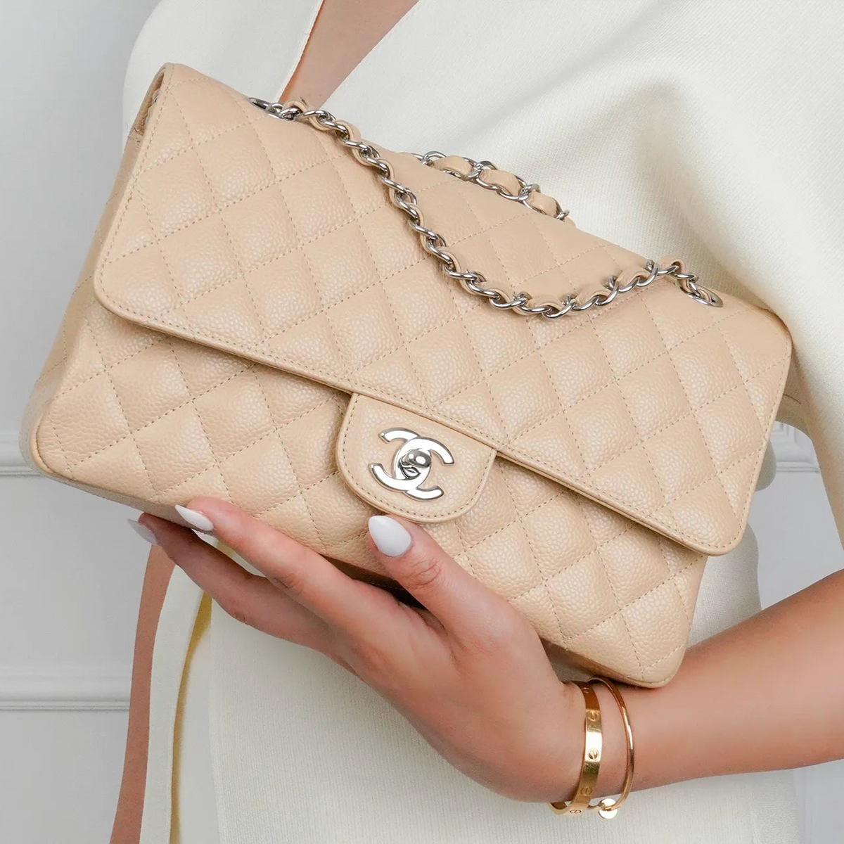 Beige quilted leather Chanel flap bag with silver chain strap, curated Pre-loved Luxury by Myluxe in Helsinki.