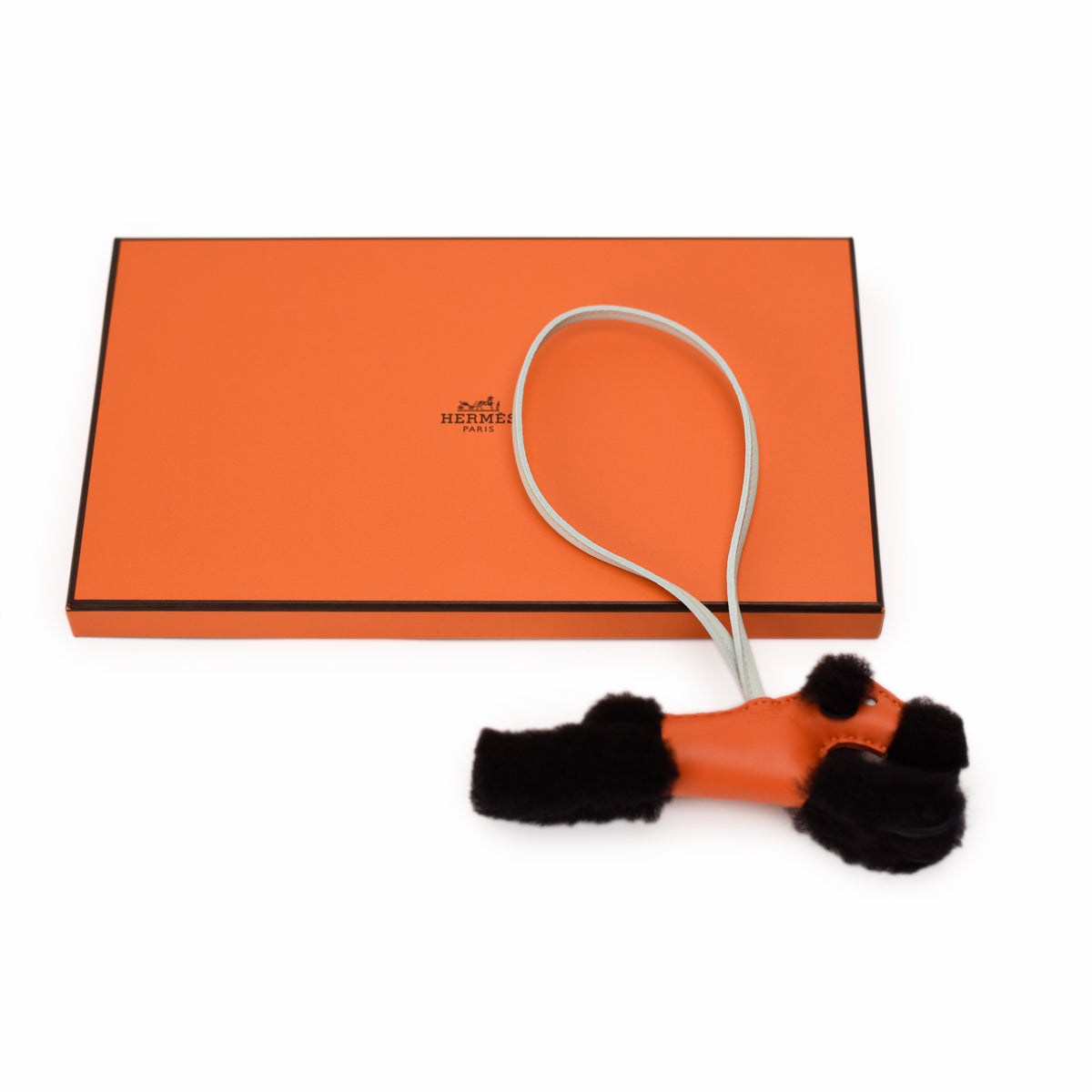 Orange Hermès box and orange leather and black fur accessory, curated Pre-loved Luxury by Myluxe in Helsinki.
