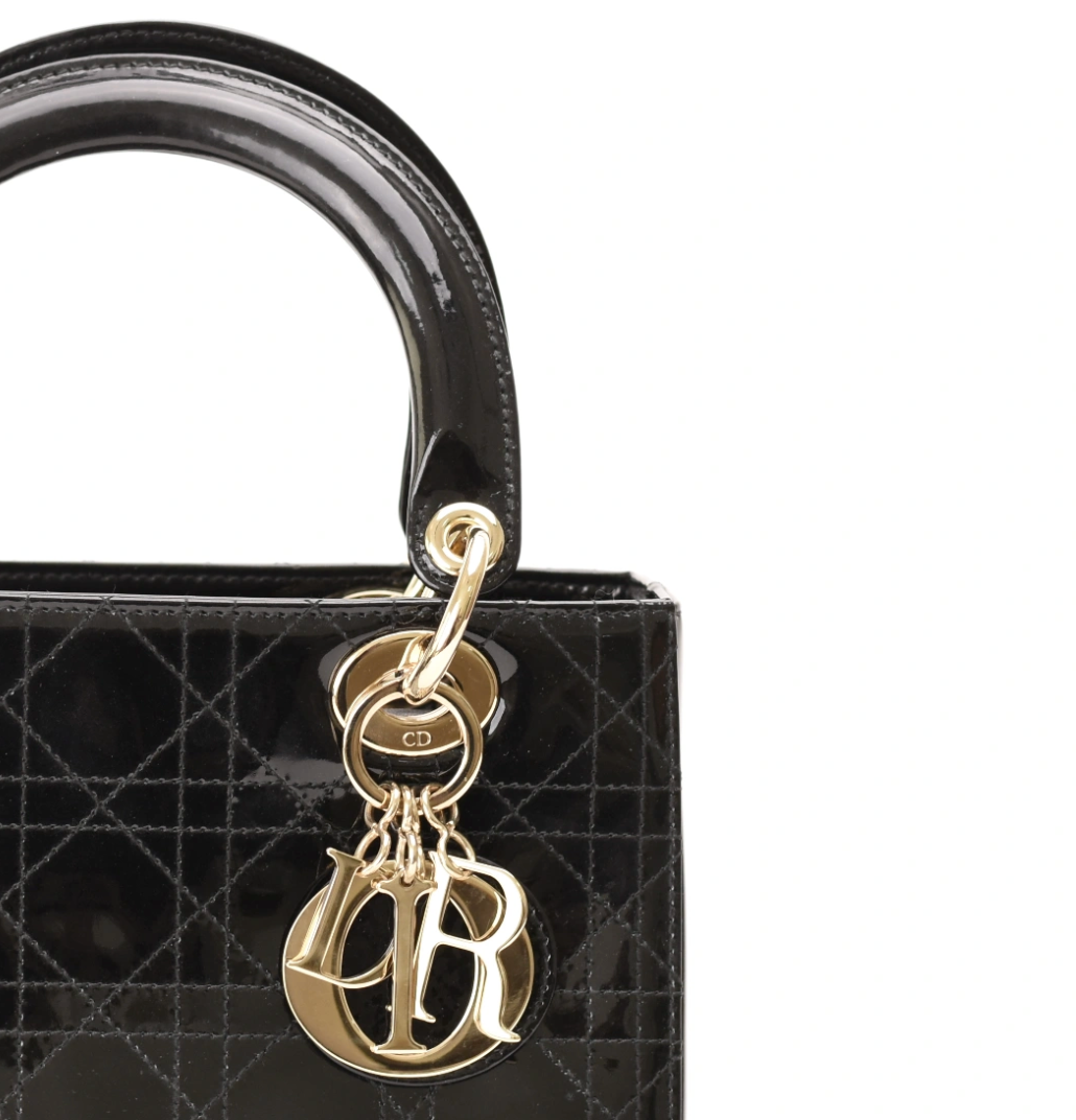 Black patent leather Dior handbag with gold-tone CD charm and monogrammed initials. curated Pre-loved Luxury by Myluxe in Helsinki.