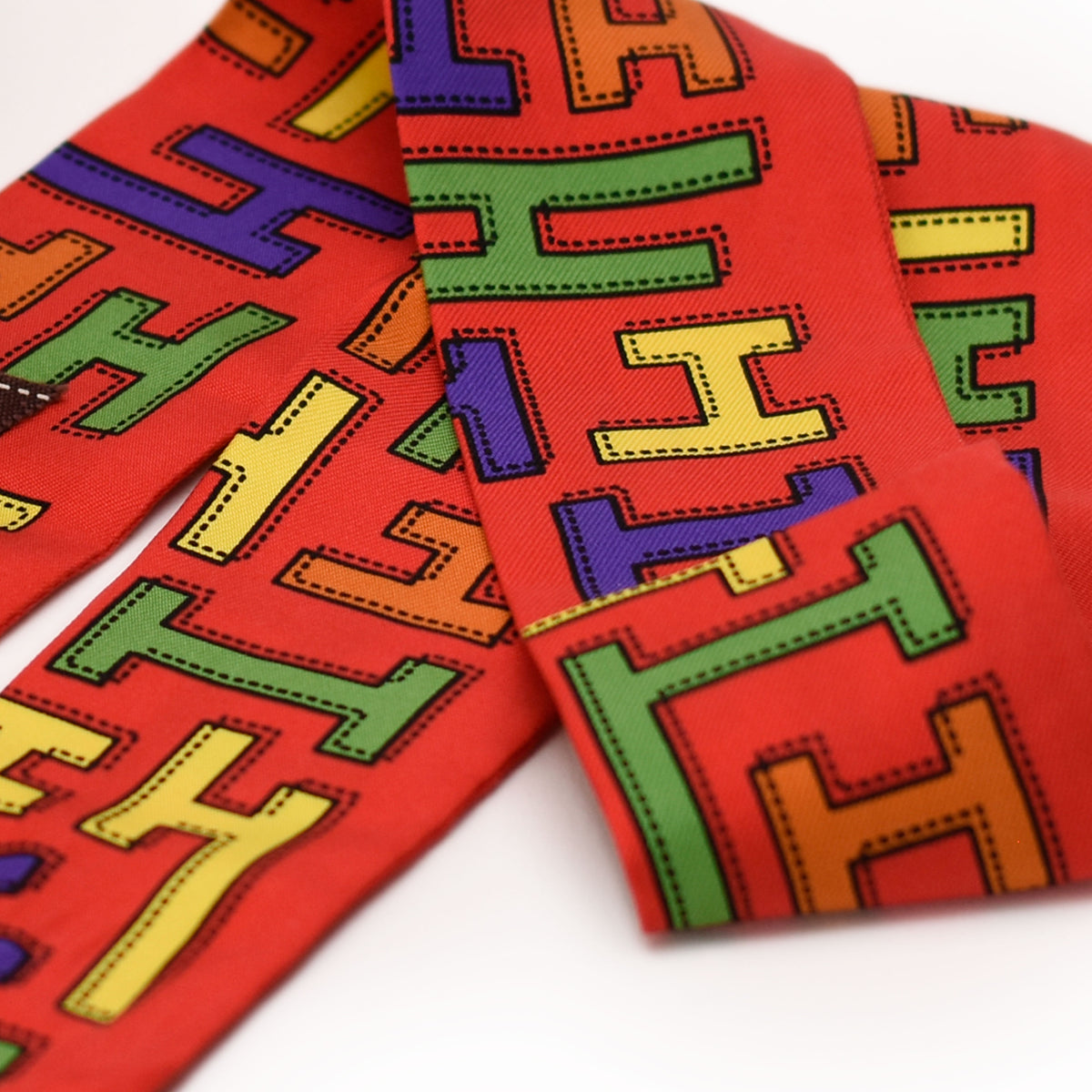 Red silk Hermès scarf with colorful graphic 'H' pattern, curated Pre-loved Luxury by Myluxe in Helsinki.