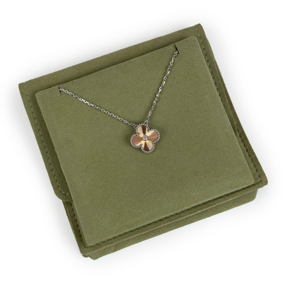 Gold-toned clover pendant necklace with a central diamond on a green velvet jewelry box, curated Pre-loved Luxury by Myluxe in Helsinki.