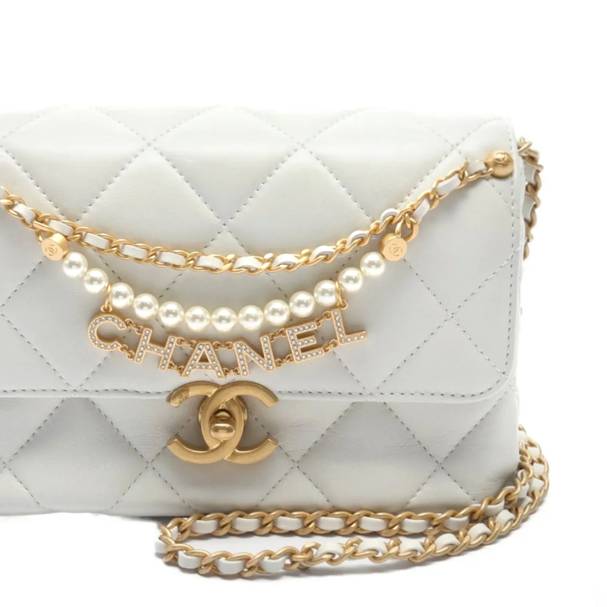 Chanel Mini Flap Bag in white with pearl accents and gold hardware, showcasing a compact, elegant handbag design.