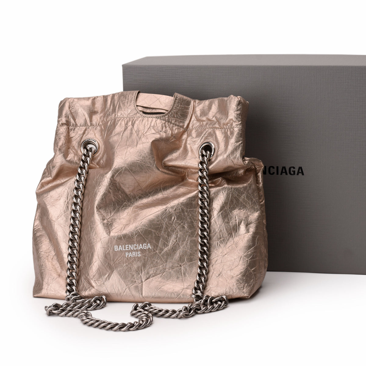 Balenciaga Paris metallic rose gold crumpled fabric bucket bag with silver chain strap, curated Pre-loved Luxury by Myluxe in Helsinki.
