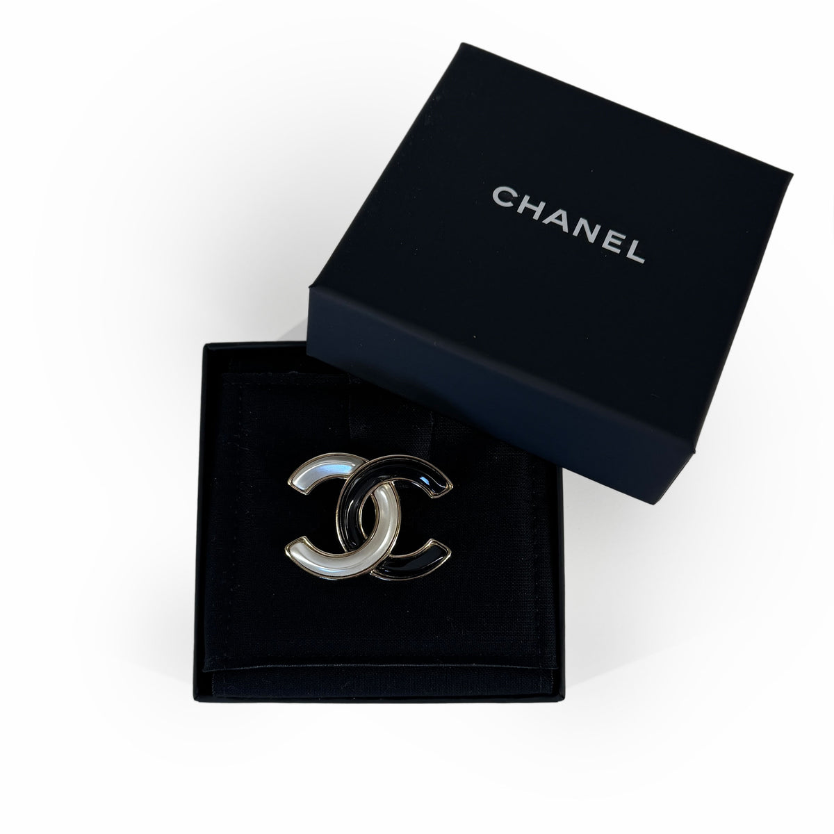Chanel interlocking CC logo brooch in silver and black enamel, curated Pre-loved Luxury by Myluxe in Helsinki.