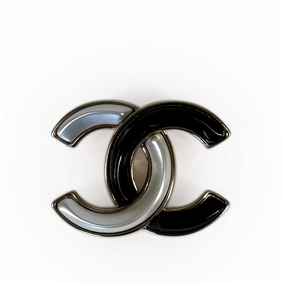 Interlocking black and silver enamel Chanel logo brooch, curated Pre-loved Luxury by Myluxe in Helsinki.