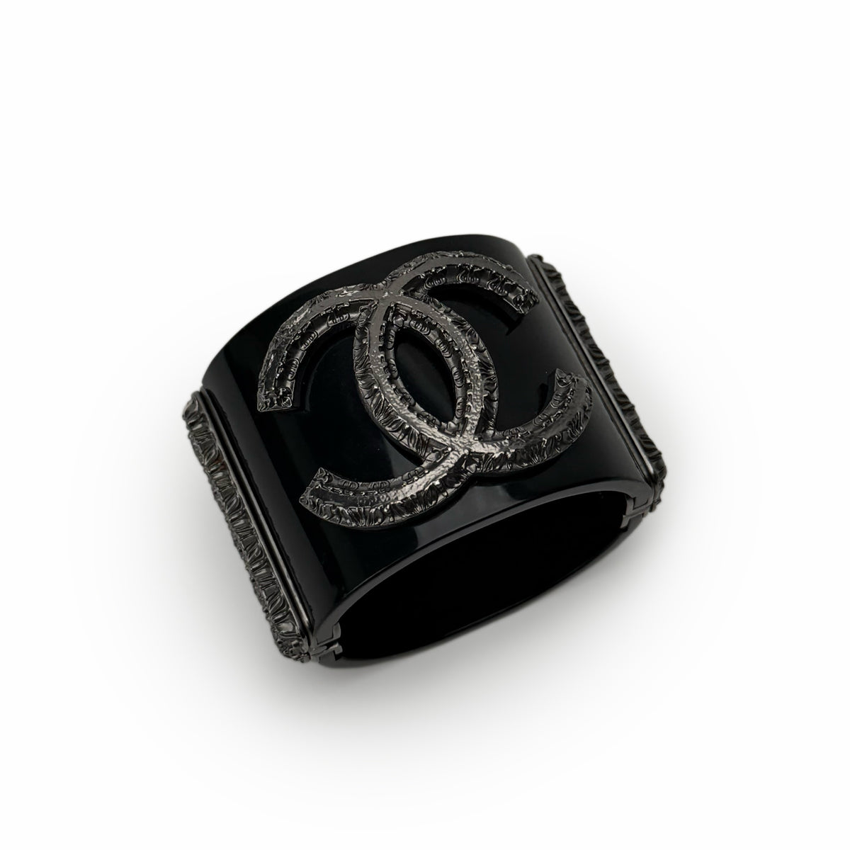 Black Chanel cuff bracelet with silver-tone interlocking CC logo, curated Pre-loved Luxury by Myluxe in Helsinki.