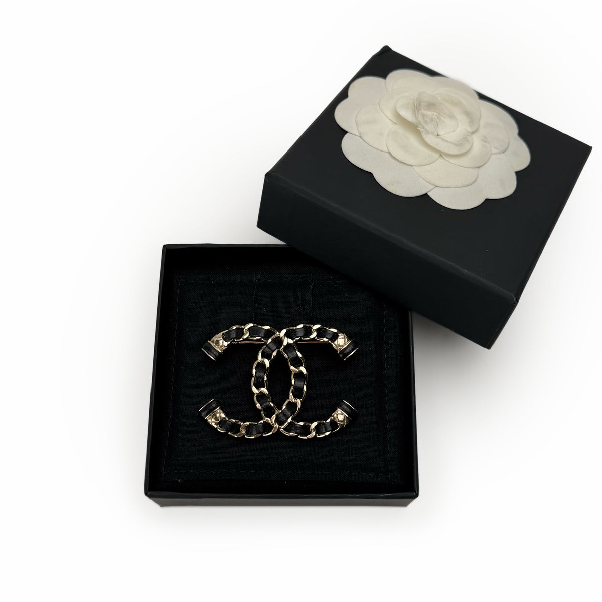 Gold-tone Chanel CC logo brooch with black leather trim, curated Pre-loved Luxury by Myluxe in Helsinki.
