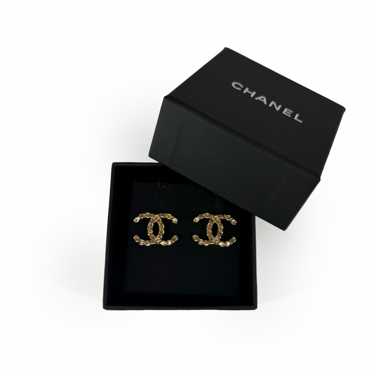 Gold-tone Chanel interlocking CC logo stud earrings in a black jewelry box, curated Pre-loved Luxury by Myluxe in Helsinki.