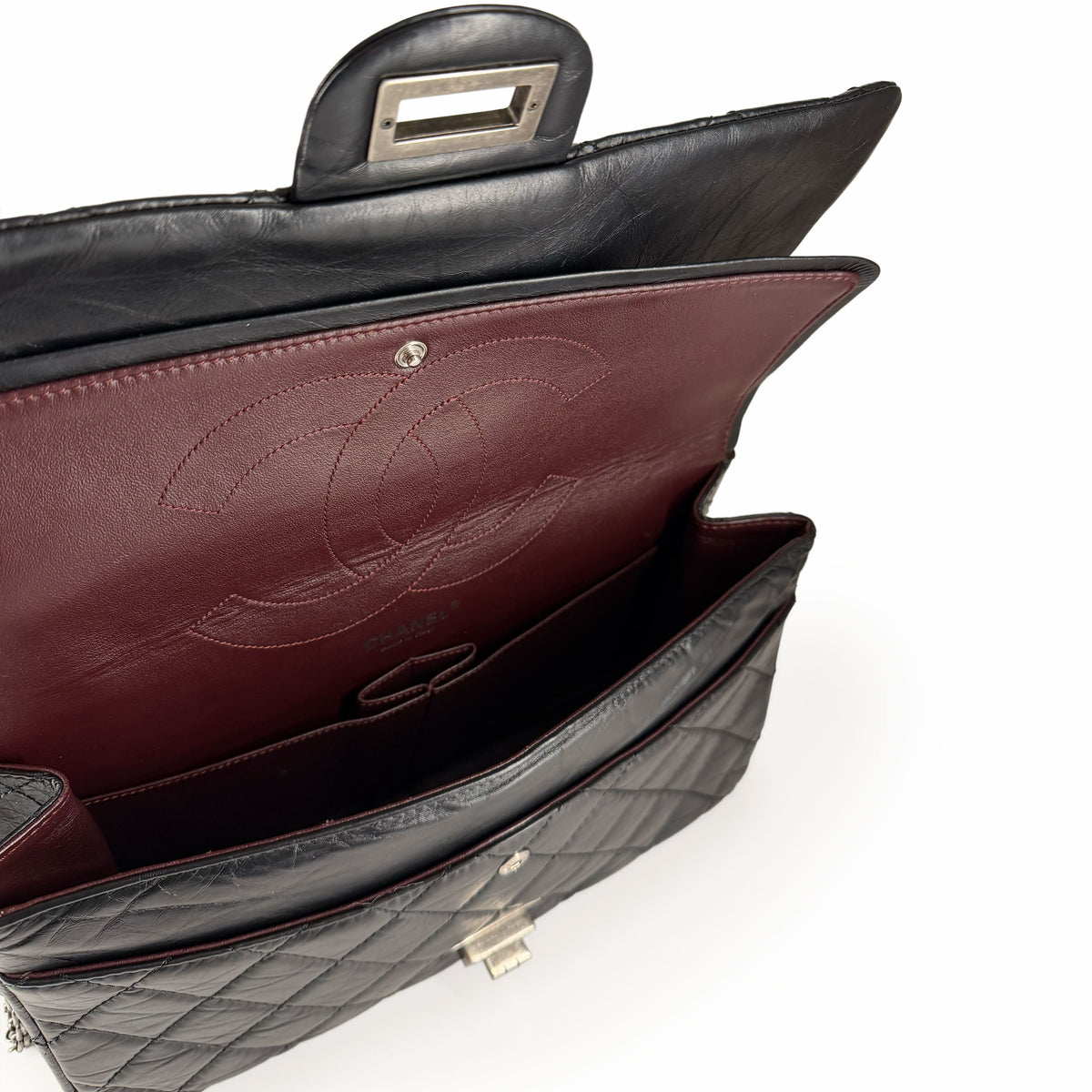 Black quilted leather Chanel flap bag with burgundy interior, curated Pre-loved Luxury by Myluxe in Helsinki.