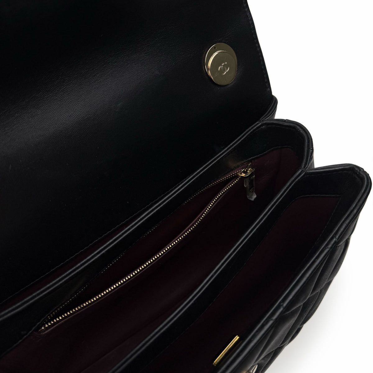 Interior of a black quilted leather Chanel handbag with a gold zipper and button, curated Pre-loved Luxury by Myluxe in Helsinki.