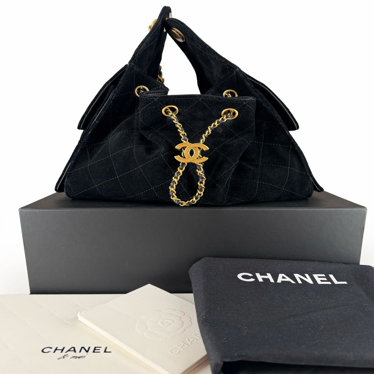 Black quilted suede Chanel handbag with gold-tone chain detail, curated Pre-loved Luxury by Myluxe in Helsinki.