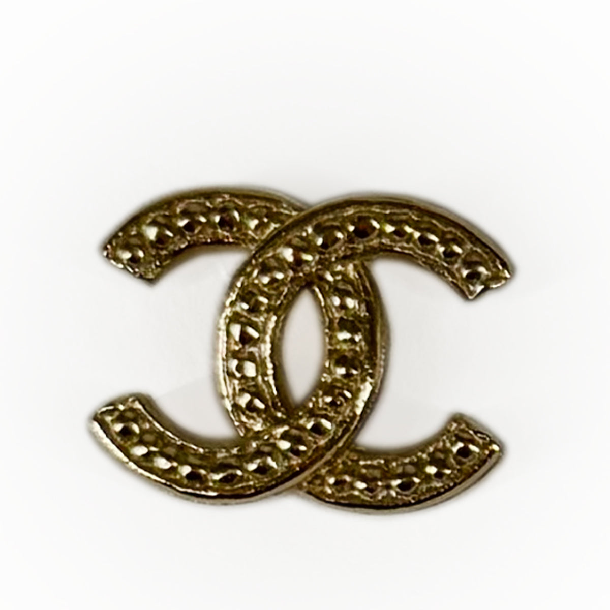 Gold-tone interlocking CC logo accessory with textured finish, curated Pre-loved Luxury by Myluxe in Helsinki.