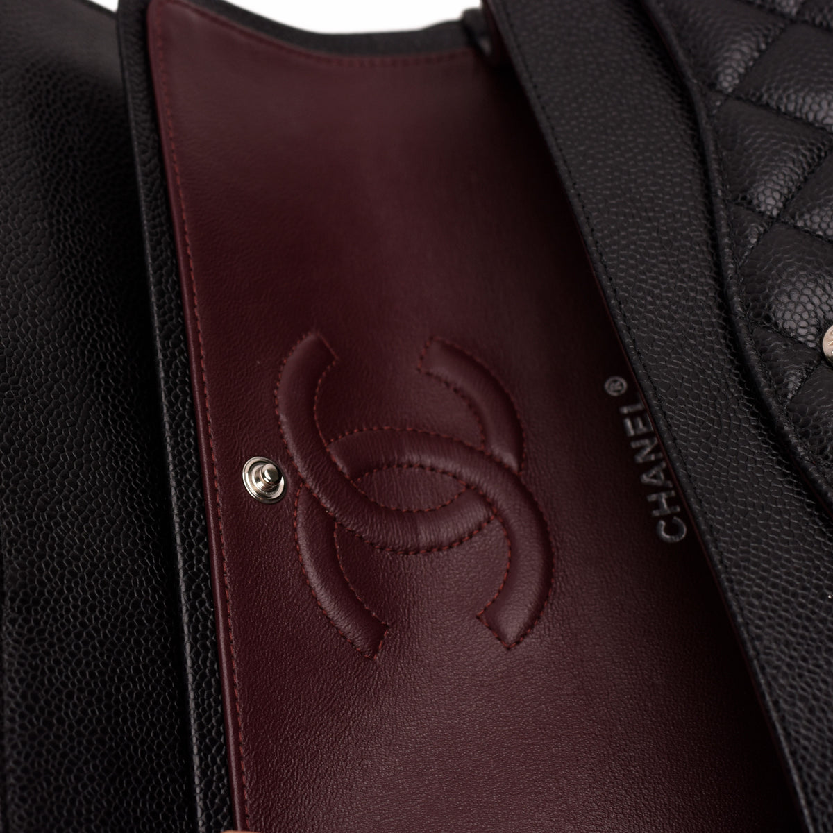 Interior of a black quilted leather Chanel handbag with burgundy lining, curated Pre-loved Luxury by Myluxe in Helsinki.