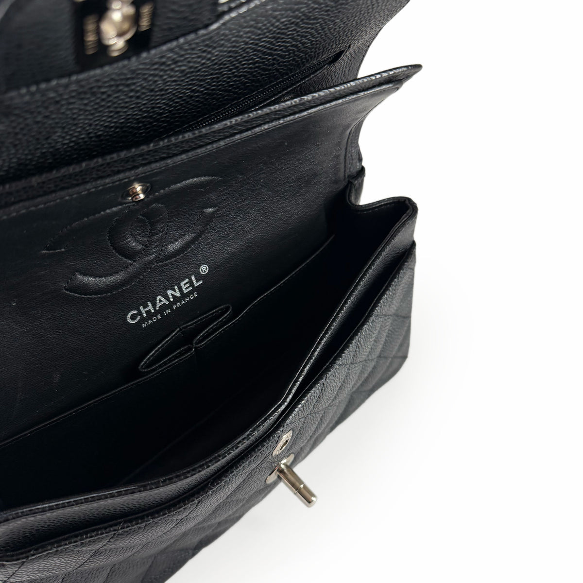 Interior of a black quilted leather Chanel handbag with silver hardware, curated Pre-loved Luxury by Myluxe in Helsinki.