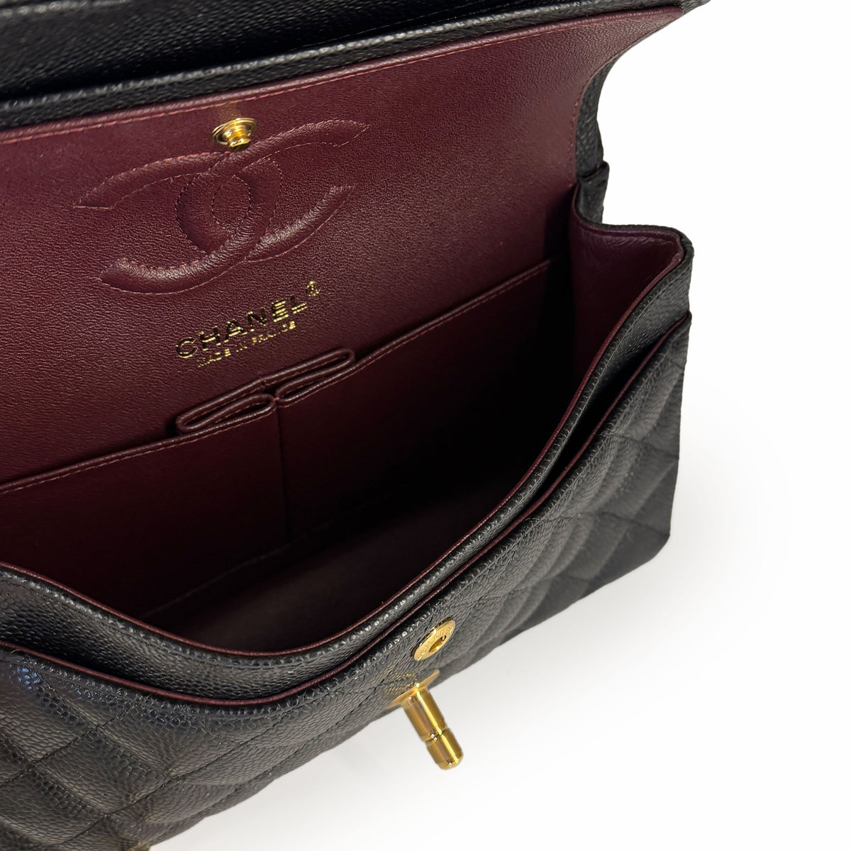 Interior of a black quilted leather Chanel handbag with burgundy lining, curated Pre-loved Luxury by Myluxe in Helsinki.
