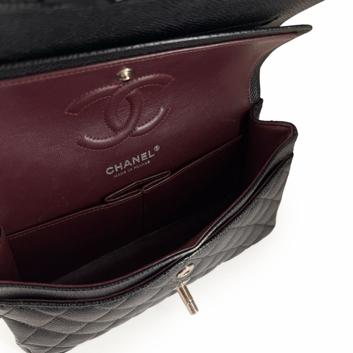 Interior of a black quilted leather Chanel handbag with burgundy lining, curated Pre-loved Luxury by Myluxe in Helsinki.