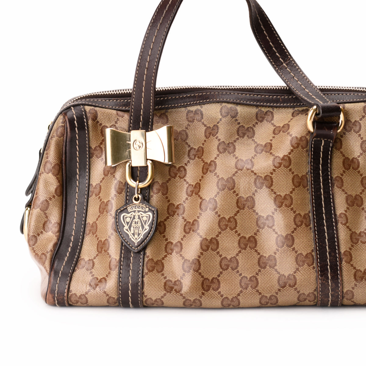 Brown Gucci GG canvas handbag with gold bow charm and leather trim, curated Pre-loved Luxury by Myluxe in Helsinki.