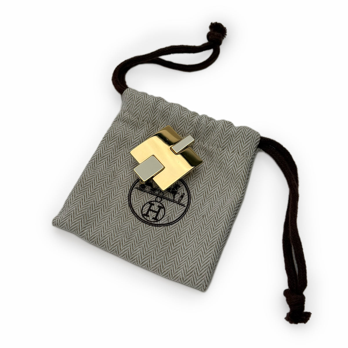 Gold-toned Hermès hardware on a grey herringbone fabric drawstring pouch, curated Pre-loved Luxury by Myluxe in Helsinki.