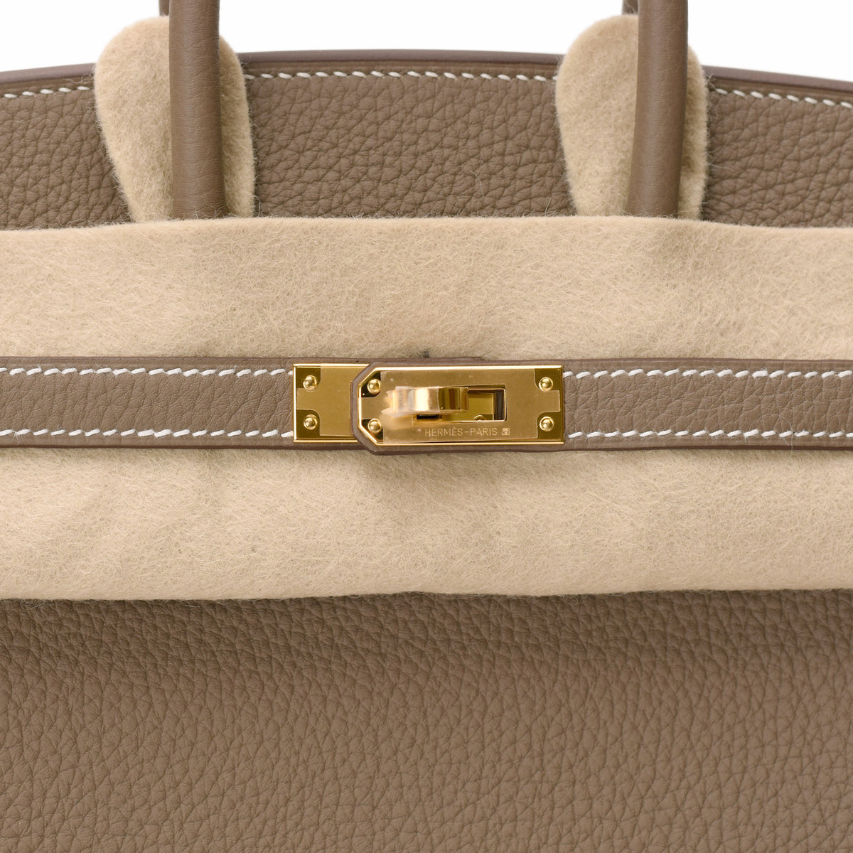 Hermès gold-tone hardware closure on taupe pebbled leather handbag. curated Pre-loved Luxury by Myluxe in Helsinki.