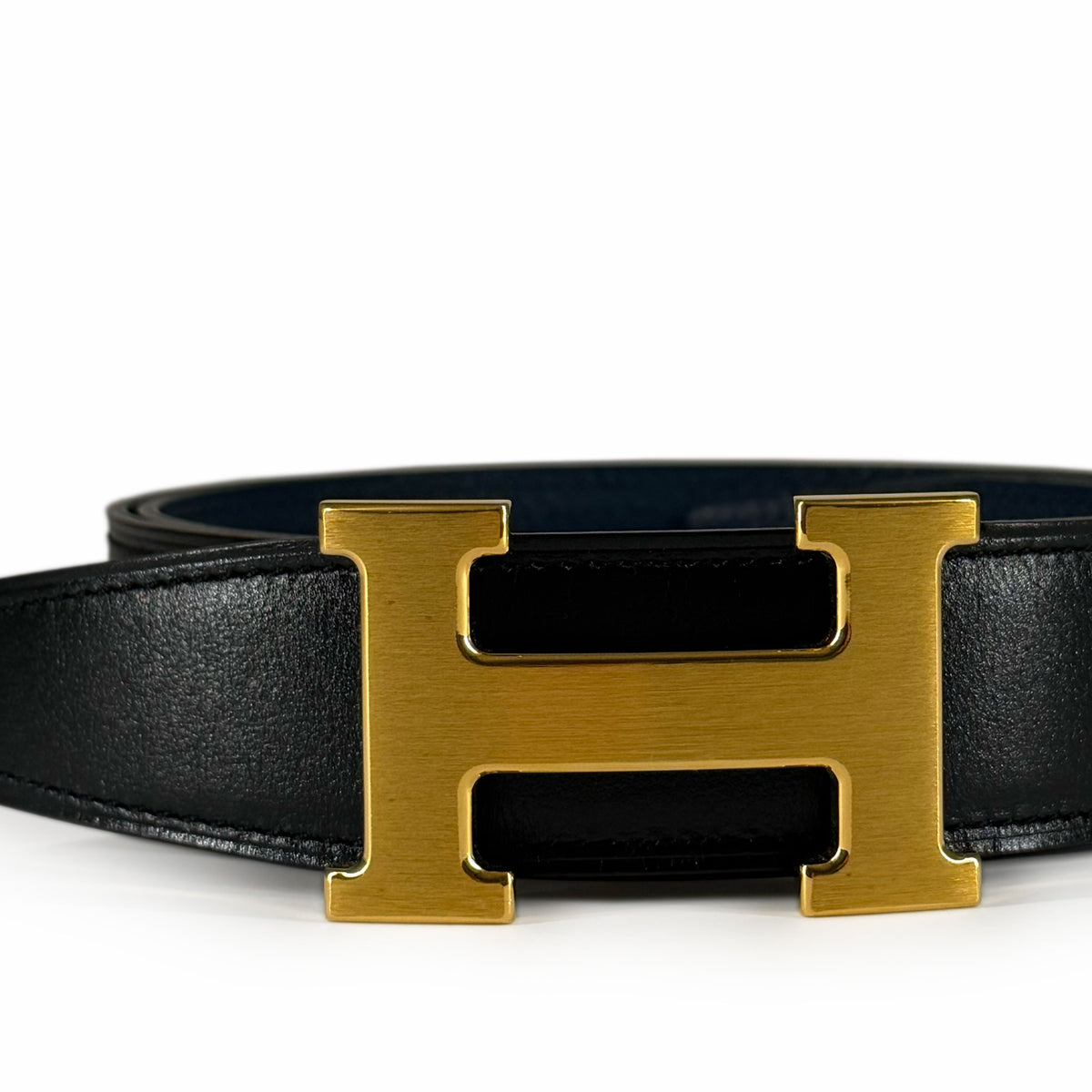 Black leather belt with a large gold-toned H-shaped buckle, curated Pre-loved Luxury by Myluxe in Helsinki.