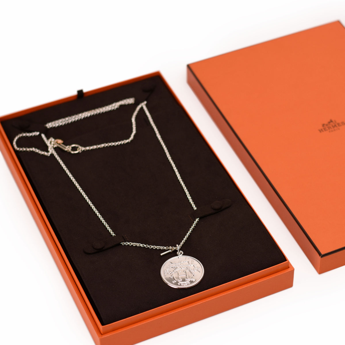 Hermès silver pendant necklace in an orange gift box. Curated Pre-loved Luxury by Myluxe in Helsinki.