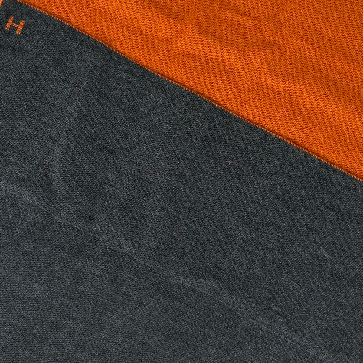 Close-up of a two-tone orange and charcoal grey cashmere scarf with an embroidered H, curated Pre-loved Luxury by Myluxe in Helsinki.