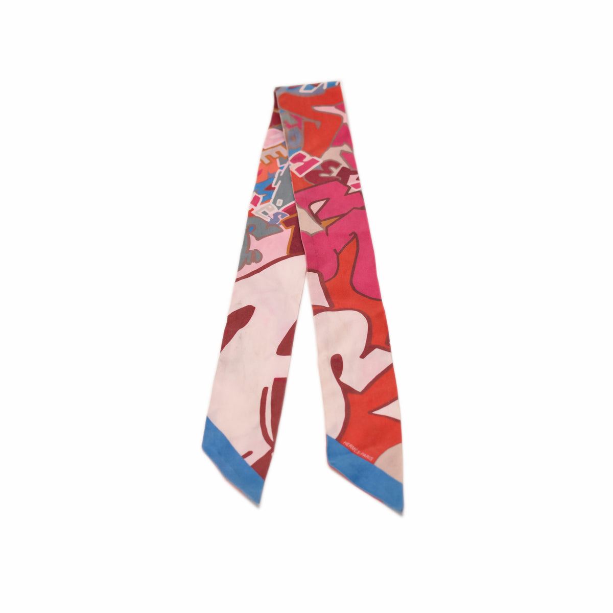 Multicolor silk Hermès twilly scarf with abstract red and pink patterns, curated Pre-loved Luxury by Myluxe in Helsinki.