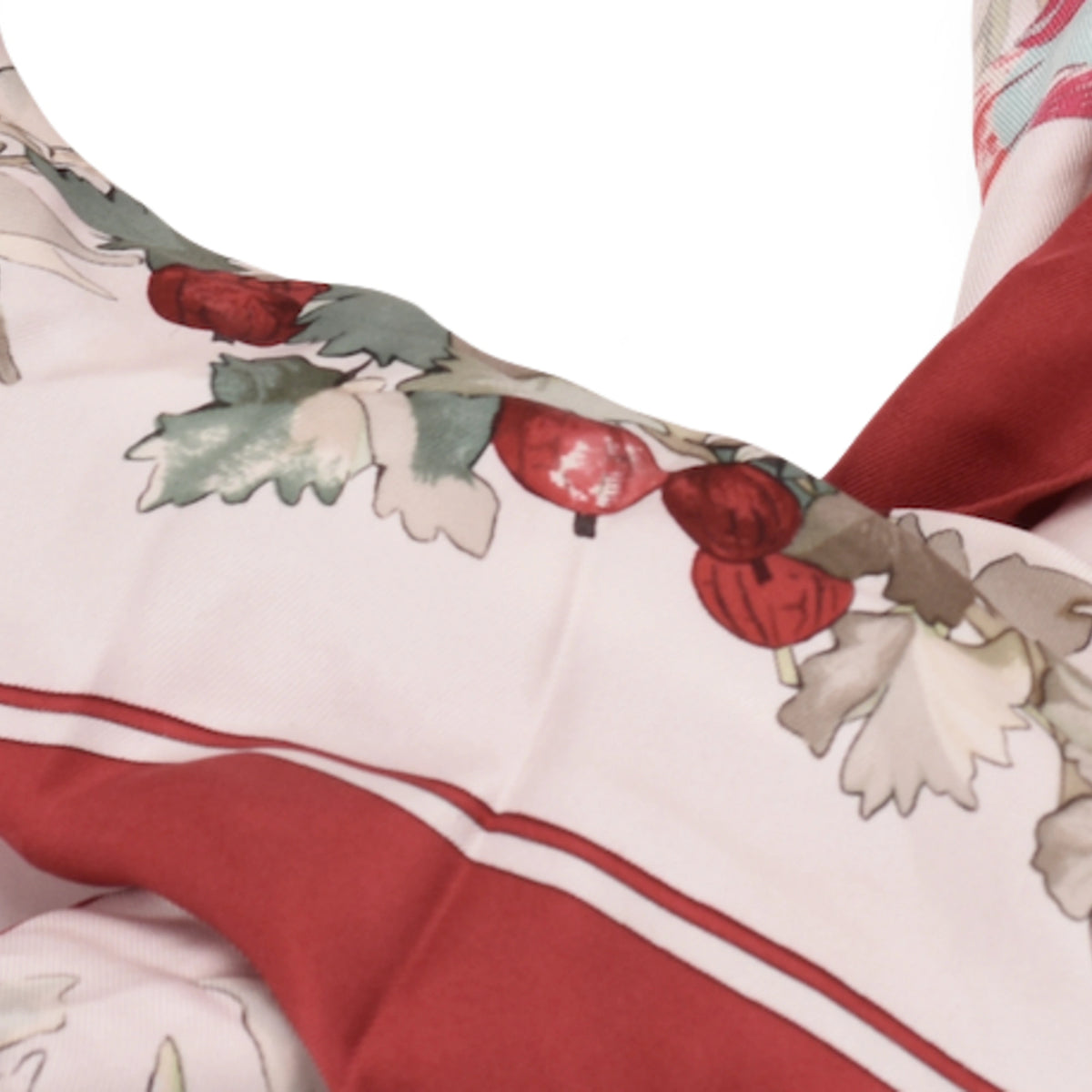 Detail of Hermès beige silk scarf with red berries and bird motifs. curated Pre-loved Luxury by Myluxe in Helsinki.
