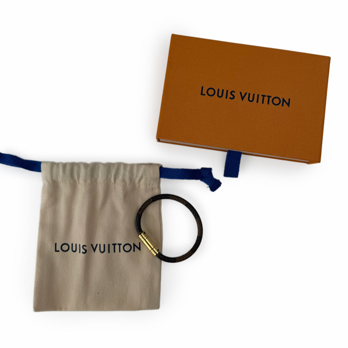 Louis Vuitton black leather bracelet with gold hardware, dust bag, and orange gift box. curated Pre-loved Luxury by Myluxe in Helsinki.