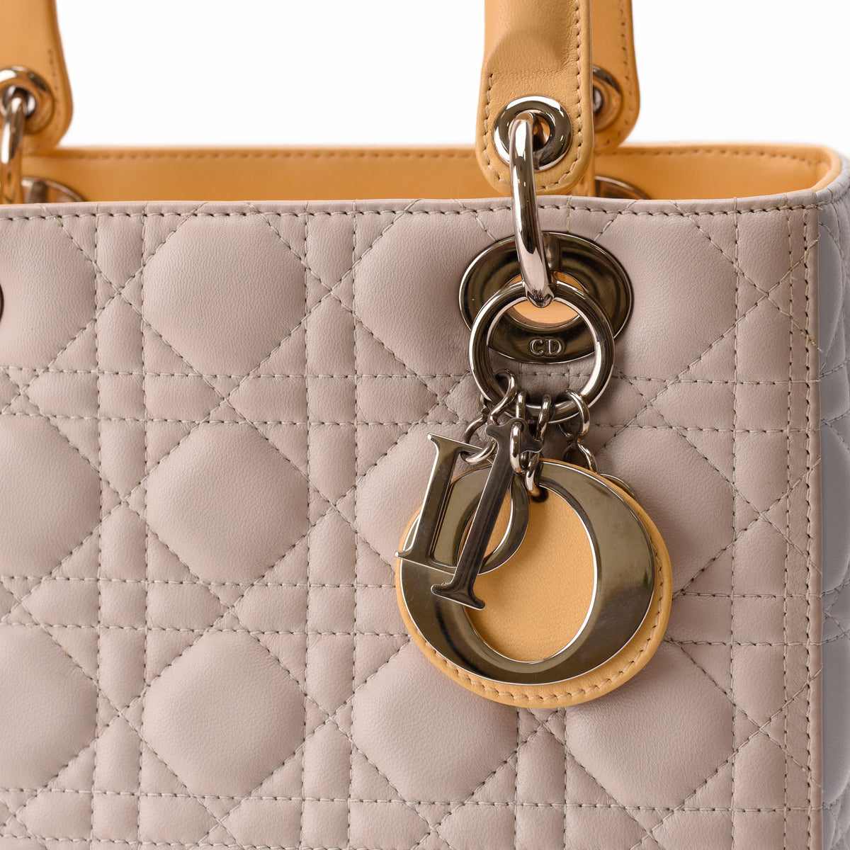 Close-up of a beige quilted Dior leather handbag with gold-tone charms, curated Pre-loved Luxury by Myluxe in Helsinki.