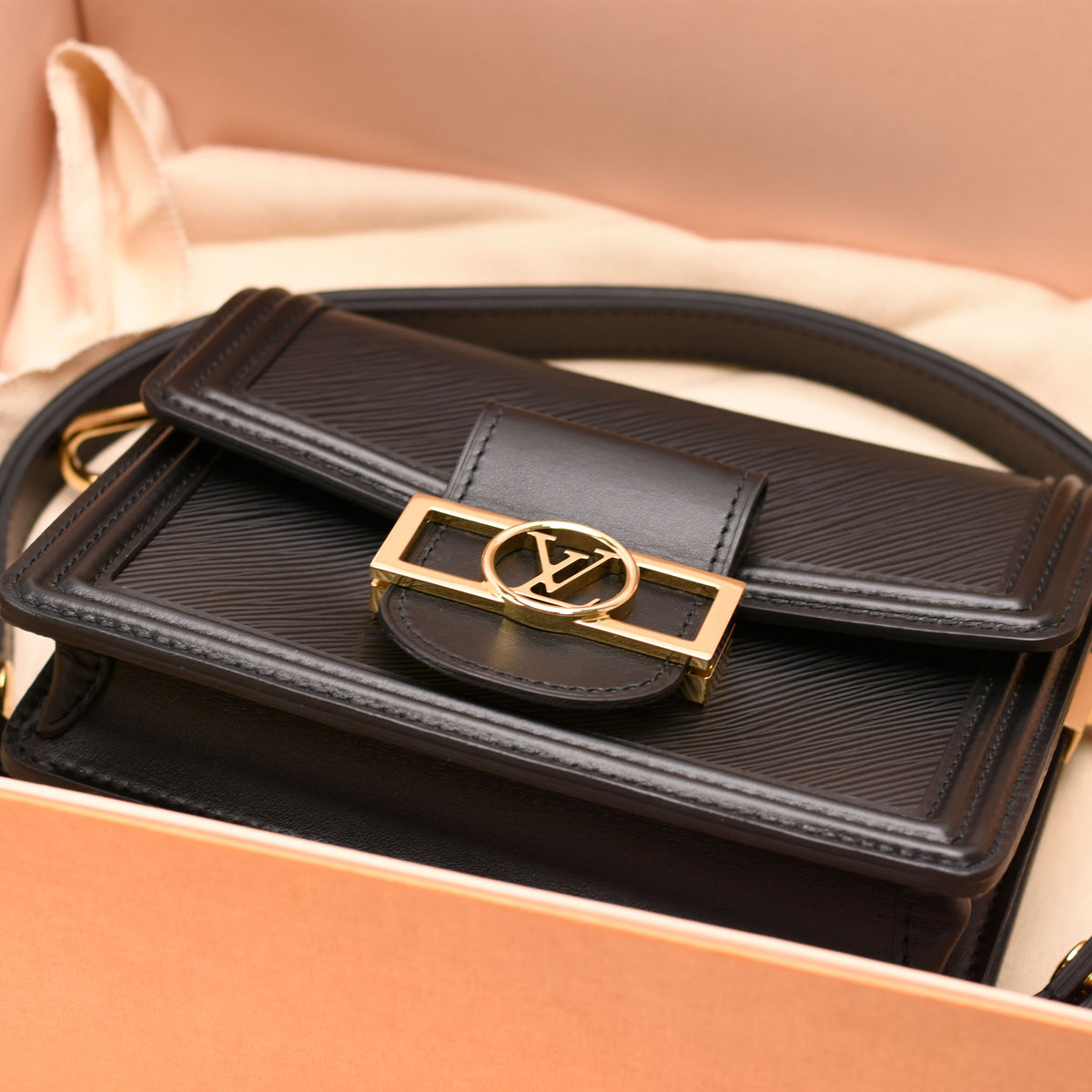 Black textured leather Louis Vuitton crossbody bag with gold-tone LV logo hardware, curated Pre-loved Luxury by Myluxe in Helsinki.