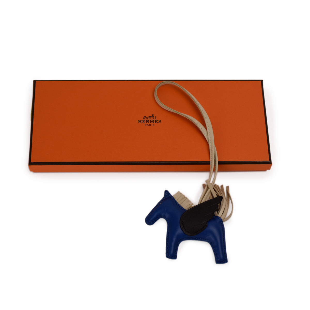 Hermès orange box with blue leather horse keychain. curated Pre-loved Luxury by Myluxe in Helsinki.